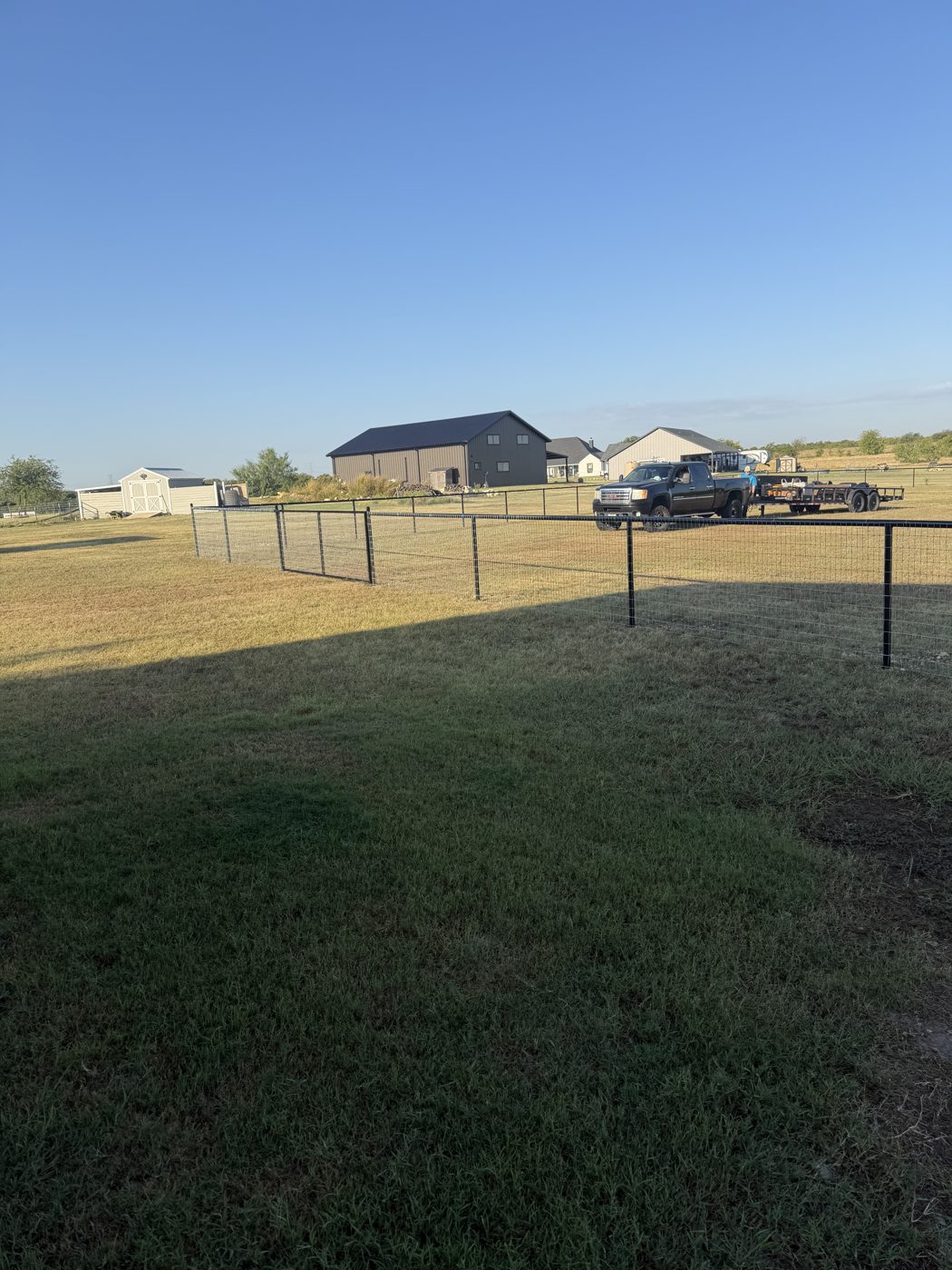 Field fence on a rural property with barn in background
