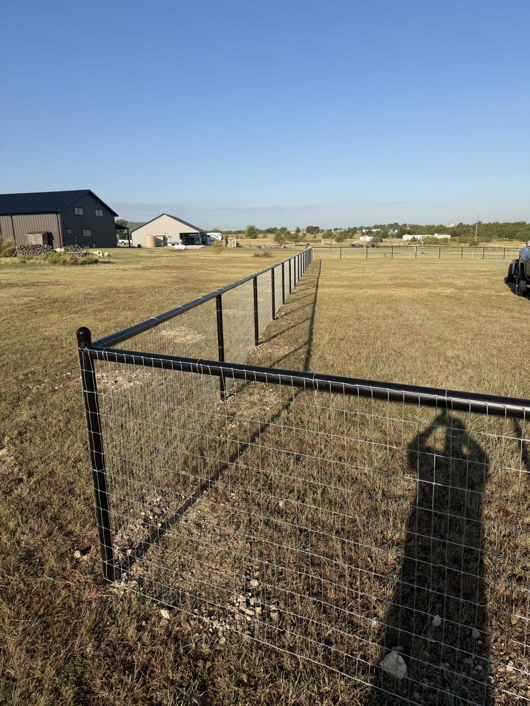 Field fence corner post with barn in background