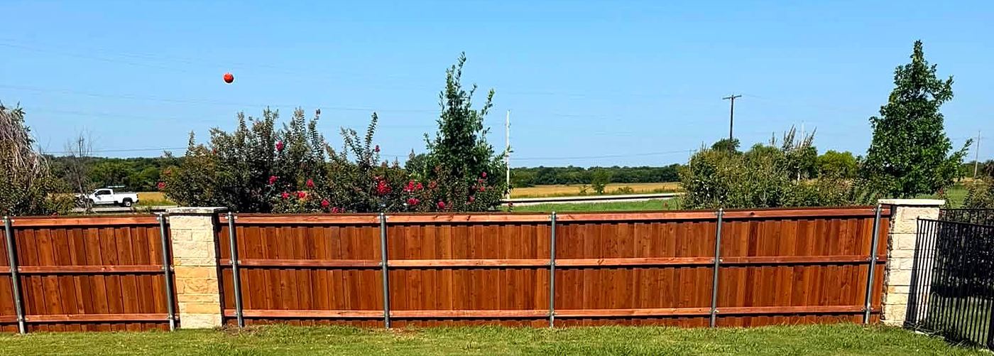 Wood fence with stone pillars and iron gate