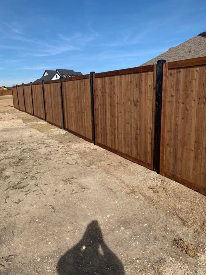 Long wood privacy fence with black metal posts
