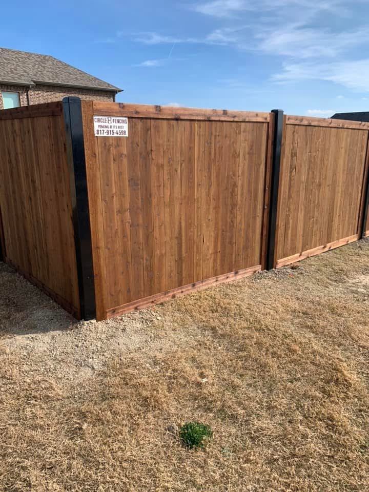 Finished wood fence with a Circle H Fencing job sign