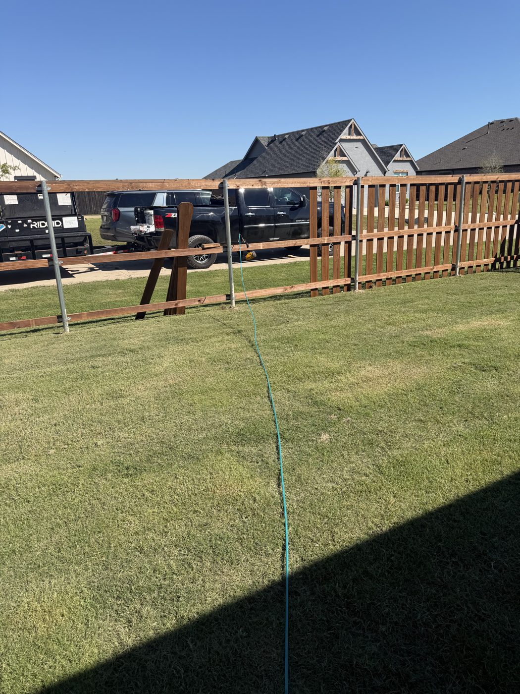 Wood picket-style fence being installed with company trailer nearby