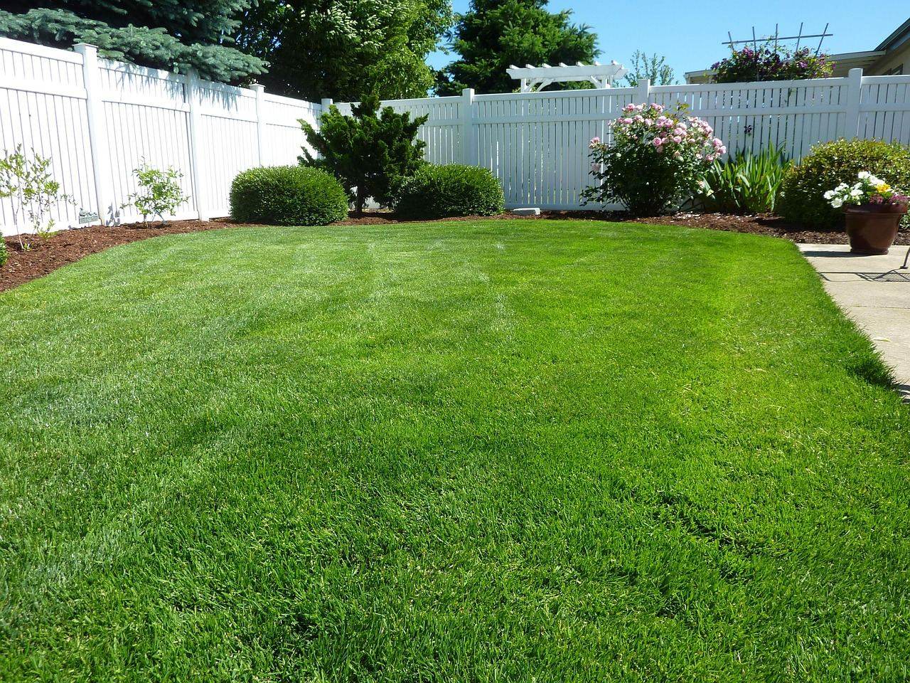 White vinyl privacy fence around a landscaped yard
